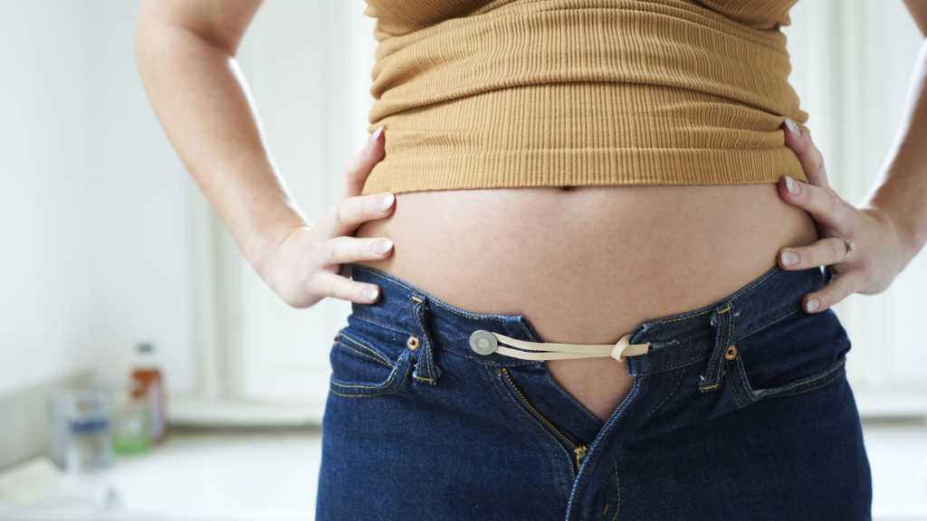 Girl with bloat belly. Half tied jeans
