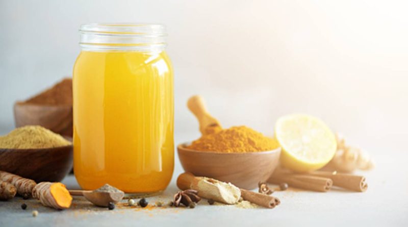 Ingredients for orange turmeric drink on grey concrete background. Lemon water with ginger, curcuma, black pepper. Vegan hot drink concept. For PCOS and Healthy Living
